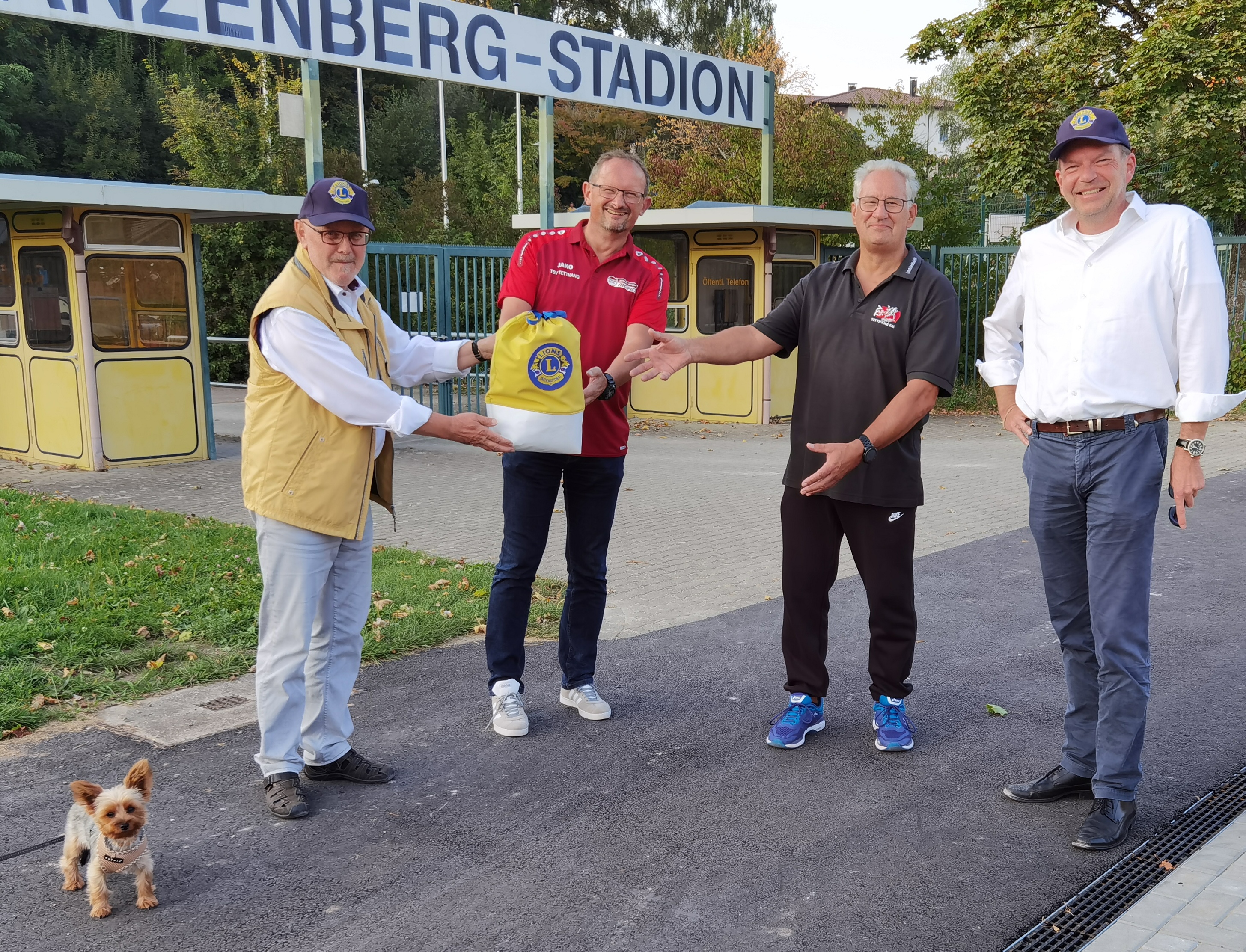 Bild zeigt die symbolische Übergabe der Spende mit dem Lions-Geldsäckchen durch Eugen Segelbacher (links) und Rainer Gutbrod (rechts) an Herrn Klaus Schwärzler (Fußball) und an Herrn Edwin Bochtler (Leichtathletik).